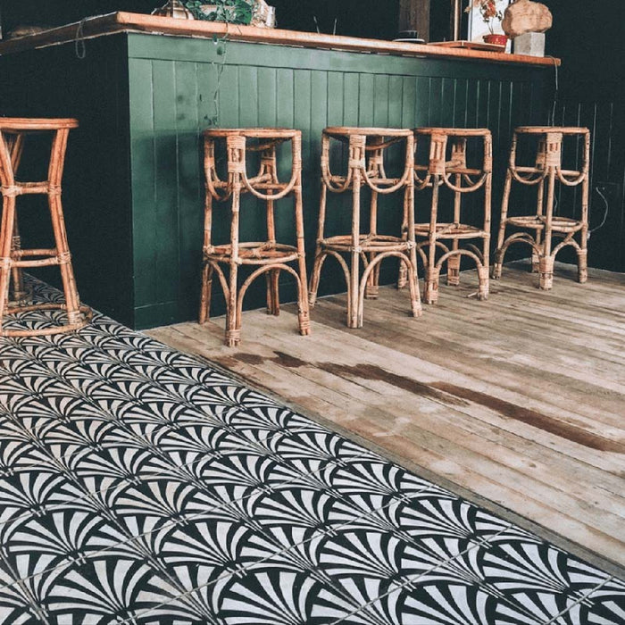 Bar area featuring Almeria Casablanca Moroccan-style porcelain floor tiles in a bold black and white fan pattern, 20x20cm, paired with wooden flooring and rattan bar stools.