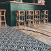 Bar area featuring Almeria Casablanca Moroccan-style porcelain floor tiles in a bold black and white fan pattern, 20x20cm, paired with wooden flooring and rattan bar stools.