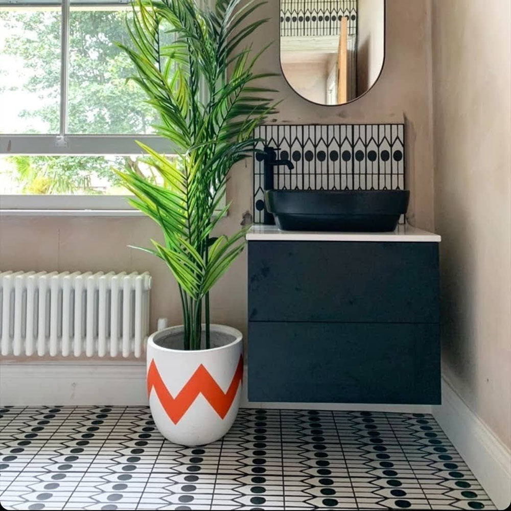 Bathroom featuring Almeria Felis Moroccan-style porcelain floor tiles in a black and white geometric dot and line pattern, 20x20cm, paired with a modern vanity unit and indoor plants.