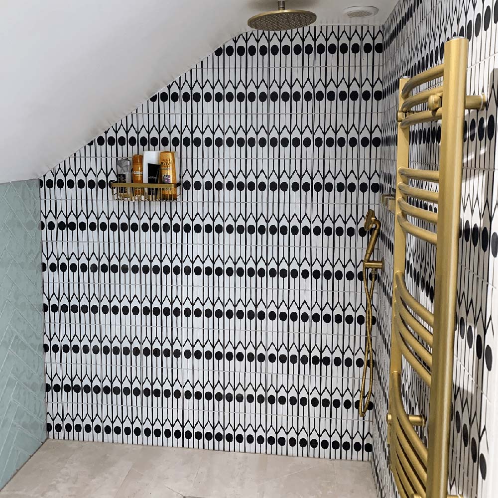 Shower area featuring Almeria Felis Moroccan-style porcelain wall tiles in a bold black and white geometric dot and line pattern, 20x20cm, paired with brass fixtures.