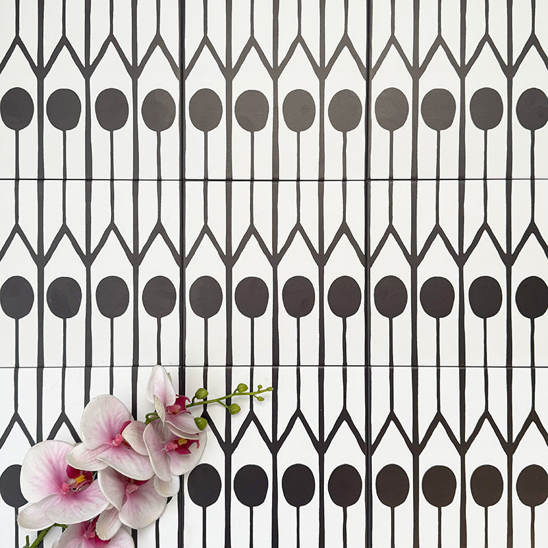 Almeria Felis Moroccan-style porcelain wall and floor tiles arranged in a repeating black and white geometric dot and line pattern, 20x20cm, styled with decorative flowers for a striking display.