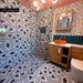 Bathroom featuring Almeira Giza 20cm x 20cm Moroccan-style wall and floor tiles, with a bold black and white geometric pattern, paired with floral wallpaper, teal tiles and a wooden vanity.