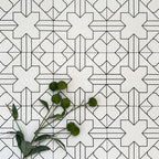 Almeria Palace Moroccan-style porcelain wall and floor tiles arranged in a repeating black line geometric pattern on a white base, 20x20cm, styled with greenery for a decorative display.