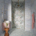Amalfi Azul Brick 5.4cm x 22cm vintage marble effect wall and floor tiles, featuring soft blue and grey tones with subtle variation across the bathroom floor, paired with marble effect wall tiles, tropical patterned tiles and warm brass details.