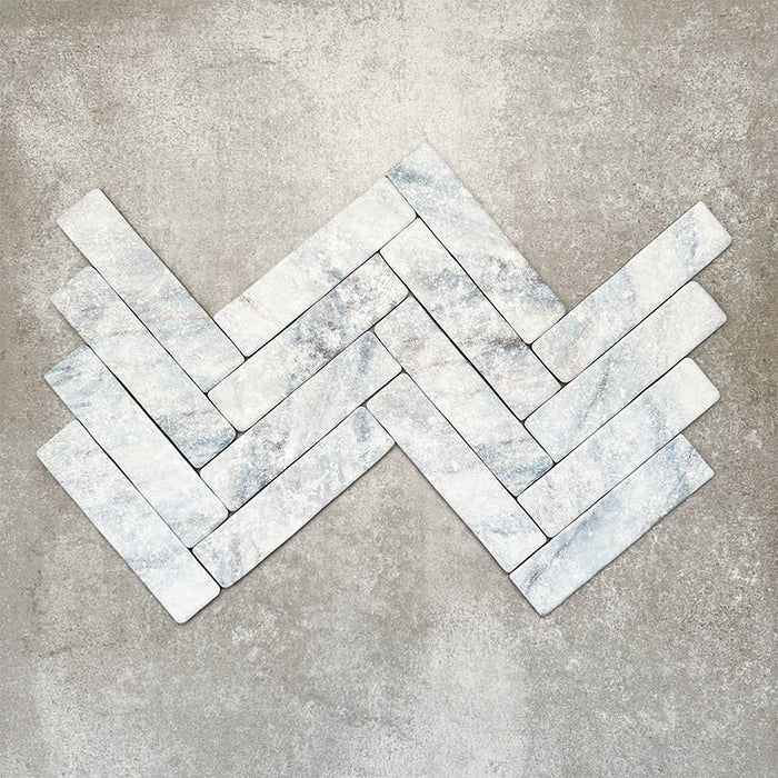 Product image of Amalfi Brick Azul Vintage Marble wall and floor tiles in a 5.4cm x 22cm format, arranged in a herringbone pattern, showcasing soft blue and white marble effect detailing with subtle veining and tonal variation.