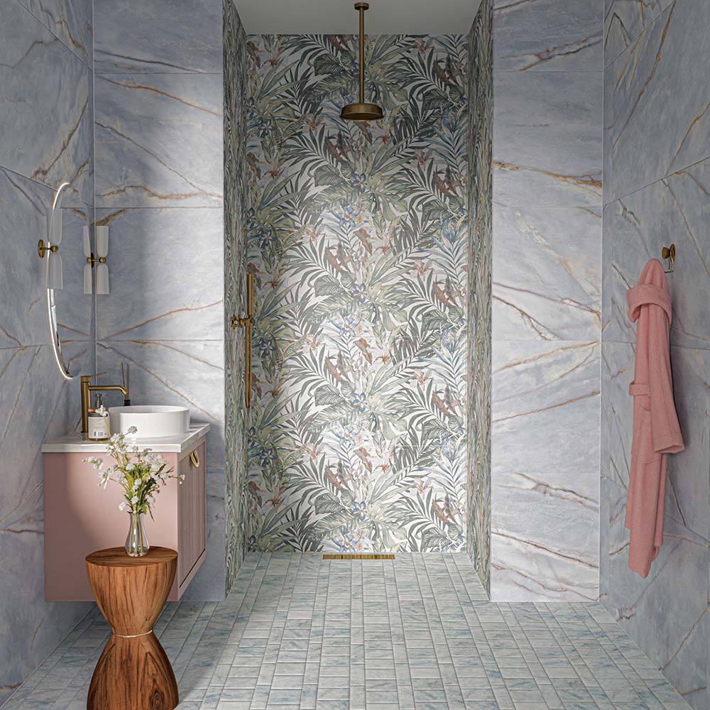 Amalfi Azul Square 11cm x 11cm vintage marble effect wall and floor tiles, featuring soft blue and grey tones with subtle variation across the bathroom floor, paired with tropical patterned tiles, large-format marble effect wall tiles and warm brass details.