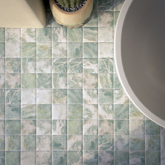Bathroom featuring Amalfi Square Salvia 11x11cm vintage marble-effect wall and floor tiles, styled with a freestanding bath, brass fixtures, and soft green glazed wall tiles for a serene Mediterranean-inspired space.