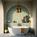 Bathroom featuring Amalfi Salvia Square 11cm x 11cm vintage marble floor tiles, with soft green and white variation, paired with green vertical wall tiles, a freestanding bath and arched detailing.