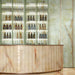 Bar interior featuring Anastasia Jade Green Onyx Polished 60 × 120cm stone effect wall and floor tiles, with soft green tones and flowing gold veining, paired with a curved bar, illuminated shelving, and warm metallic accents.