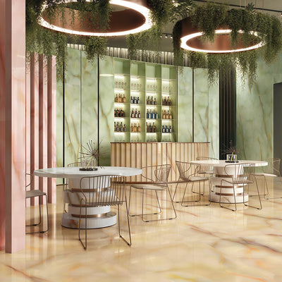 Restaurant interior featuring Anastasia Miele Onyx Matt 60 × 120cm stone effect floor and wall tiles, with warm honey tones and soft veining, paired with curved tables, metallic chairs, green panels, and statement lighting.