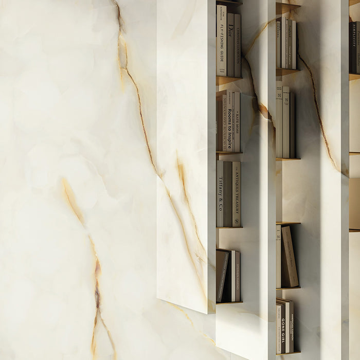 Interior wall featuring Anastasia Pearl Onyx Matt 60 × 120cm stone effect tiles, with soft cream tones and flowing gold veining, styled with built-in shelving and warm lighting to highlight depth and texture.