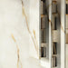 Interior wall featuring Anastasia Pearl Onyx Matt 60 × 120cm stone effect tiles, with soft cream tones and flowing gold veining, styled with built-in shelving and warm lighting to highlight depth and texture.