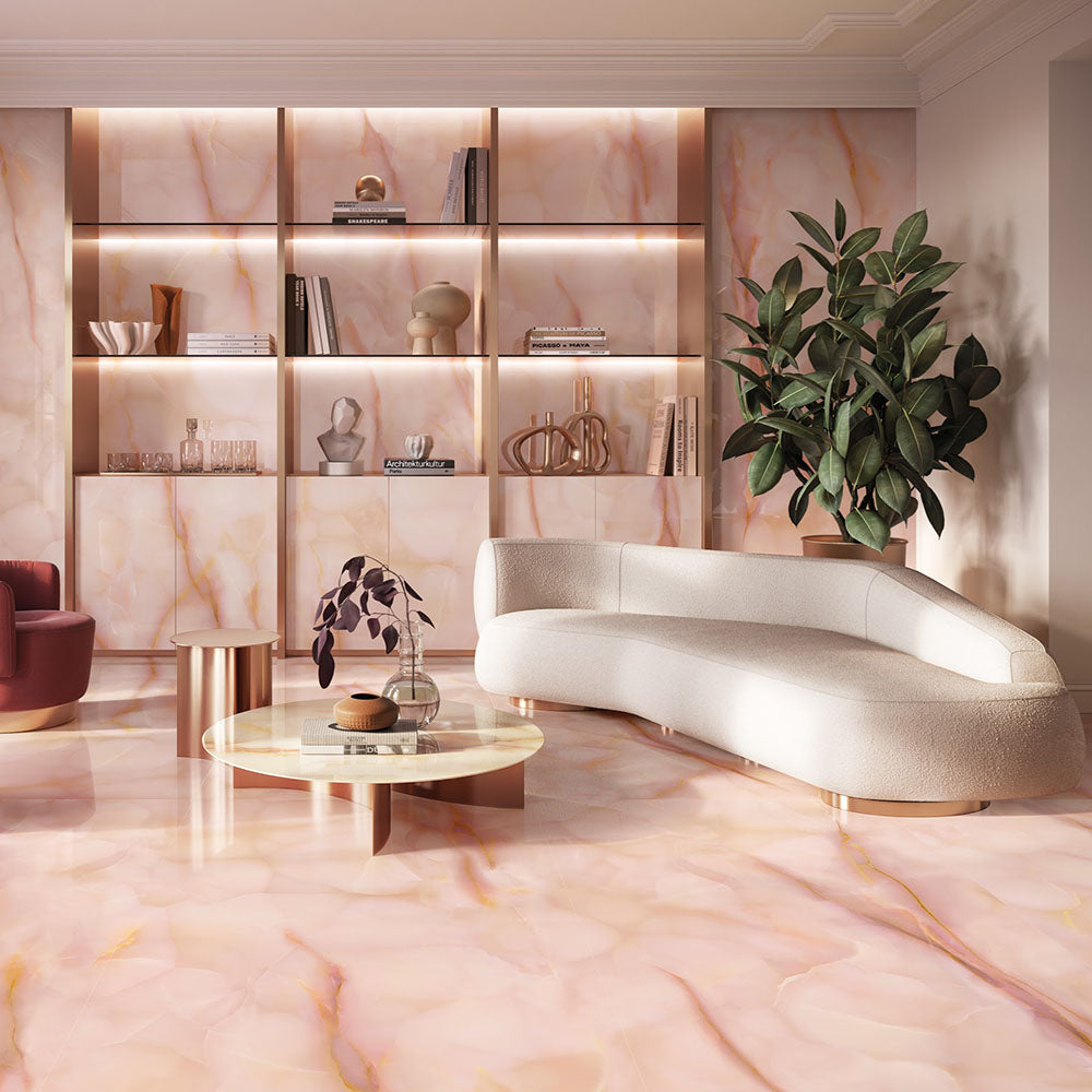 Living room featuring Anastasia Rose Onyx Matt 60 × 120cm stone effect floor and wall tiles, with soft pink tones and delicate gold veining, paired with curved seating, warm lighting, and built-in shelving.
