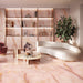 Living room featuring Anastasia Rose Onyx Matt 60 × 120cm stone effect floor and wall tiles, with soft pink tones and delicate gold veining, paired with curved seating, warm lighting, and built-in shelving.
