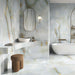 Bathroom interior featuring Anastasia Turchese Blue Onyx Matt 60 × 120cm stone effect wall and floor tiles, with soft blue tones and flowing gold veining, paired with a freestanding bath, built-in shelving, and brass fittings.