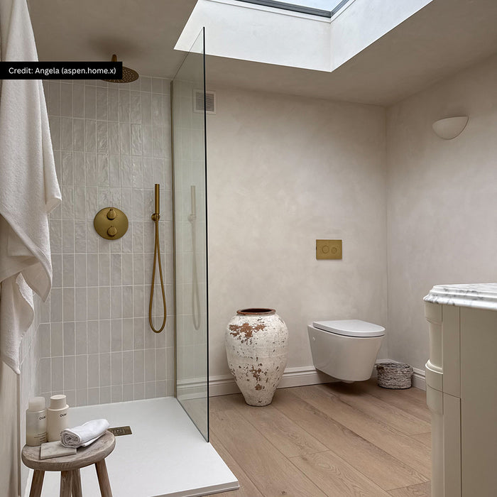 Bathroom interior featuring Zellige Oyster Brick 6.5x20cm Moroccan style tiles in soft neutral tones, installed vertically in a walk-in shower, styled with brass shower fittings, glass screen and natural textures in a calm contemporary space.