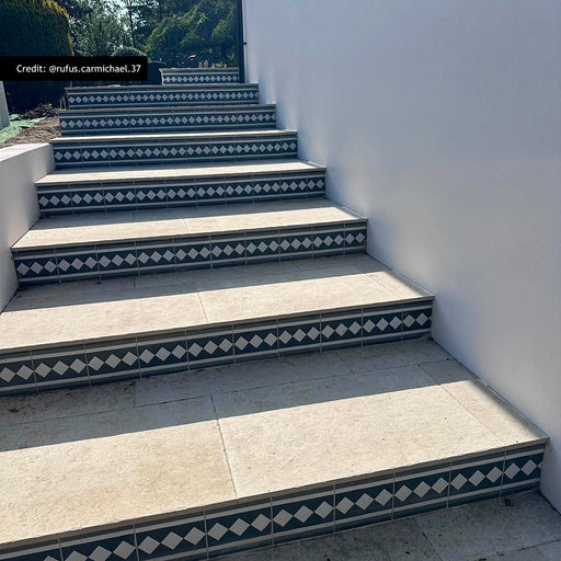 Outdoor steps featuring Aston Manor Victorian style border tiles in 20cm x 20cm. Decorative black and white Victorian style border tiles highlight each step, paired with large stone effect porcelain paving for a timeless and elegant garden entrance.
