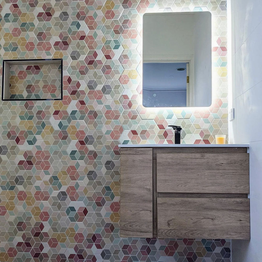 Bathroom featuring Athens Multicoloured Hexagon Patchwork 17 × 15cm Moroccan-style wall tiles, forming a vibrant geometric feature wall, paired with a floating wood-effect vanity, illuminated mirror and matte black tapware.