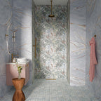Bahamas 60cm x 120cm marble effect porcelain wall and floor tiles, featuring soft blue and grey tones with delicate warm veining, paired with tropical patterned tiles, blush pink cabinetry and warm brass details.