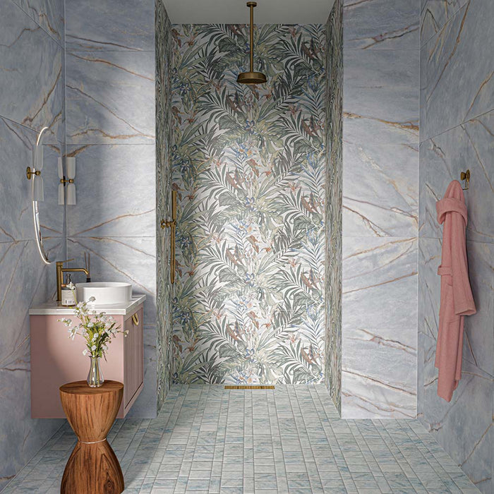 Bahamas 60cm x 120cm marble effect porcelain wall and floor tiles, featuring soft blue and grey tones with delicate warm veining, paired with tropical patterned tiles, blush pink cabinetry and warm brass details.