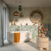 Baresi Puro Light 3D 60cm x 60cm terrazzo effect tiles, covering the bathroom walls and floor in warm neutral tones, paired with green patterned tiles, a freestanding bath and brass fittings.