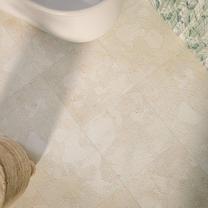 Baresi Puro Light 3D 60cm x 60cm terrazzo effect floor tiles, featuring a textured warm cream and beige finish, paired with green patterned wall tiles in a contemporary bathroom.