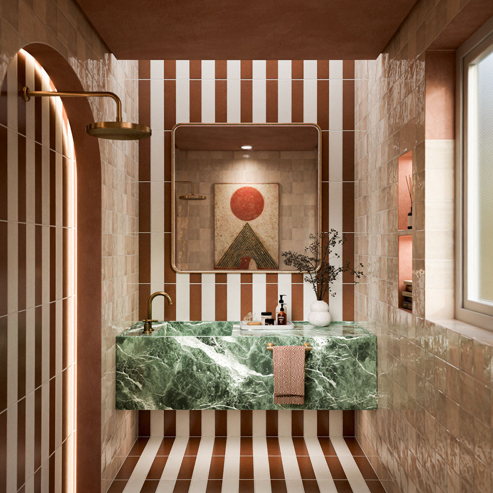 Bathroom featuring Baroque Cotto 9.1cm x 37.5cm porcelain wall and floor tiles, arranged in a striped design with white tiles, glossy neutral walls, green marble vanity and brass fixtures.
