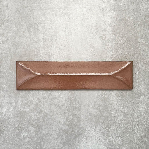 Baroque Decor Cotto porcelain wall tile in a 9.1cm x 37.5cm format, featuring a warm terracotta metallic finish with a raised geometric relief design and gently distressed edges, displayed against a textured concrete-effect background.