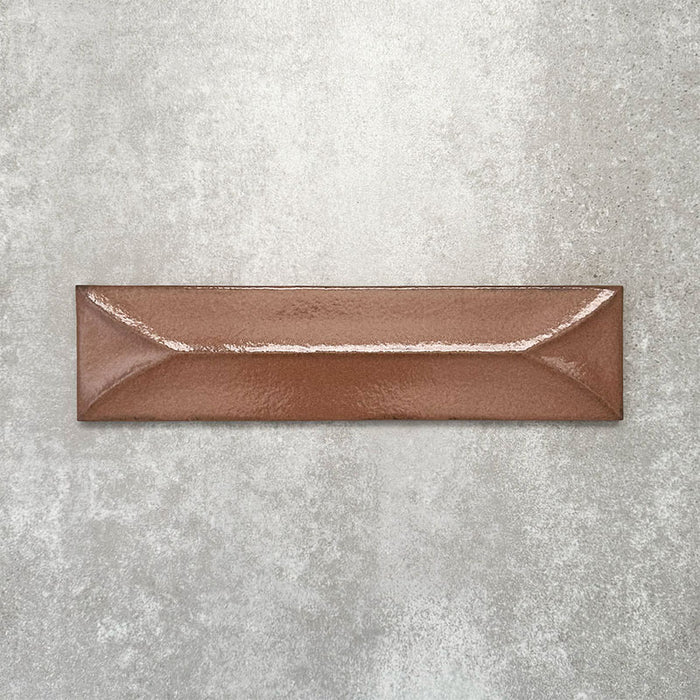 Baroque Decor Cotto porcelain wall tile in a 9.1cm x 37.5cm format, featuring a warm terracotta metallic finish with a raised geometric relief design and gently distressed edges, displayed against a textured concrete-effect background.