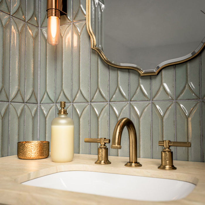 Bathroom vanity area featuring Baroque Decor Lichen Green 9.1x37.5cm porcelain wall tiles, showcasing a glossy fluted design in soft green tones, paired with a stone basin, brass fittings and warm ambient lighting.