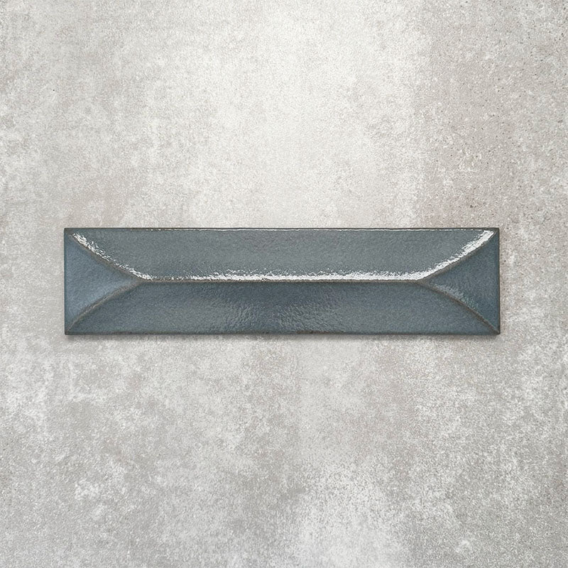 Baroque Decor Laguna Blue porcelain wall tile in a 9.1cm x 37.5cm format, featuring a deep blue metallic finish with a raised geometric relief design and gently distressed edges, displayed against a textured concrete-effect background.