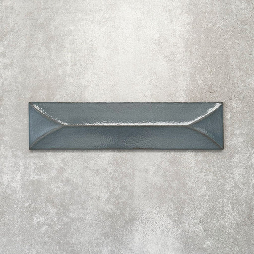 Baroque Decor Laguna Blue porcelain wall tile in a 9.1cm x 37.5cm format, featuring a deep blue metallic finish with a raised geometric relief design and gently distressed edges, displayed against a textured concrete-effect background.