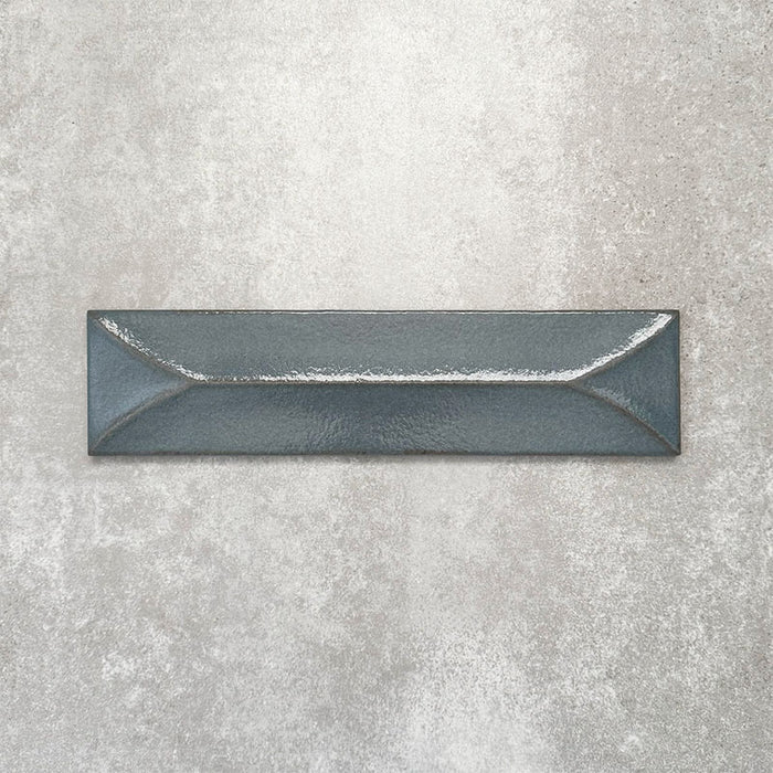 Baroque Decor Laguna Blue porcelain wall tile in a 9.1cm x 37.5cm format, featuring a deep blue metallic finish with a raised geometric relief design and gently distressed edges, displayed against a textured concrete-effect background.