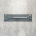Baroque Decor Laguna Blue porcelain wall tile in a 9.1cm x 37.5cm format, featuring a deep blue metallic finish with a raised geometric relief design and gently distressed edges, displayed against a textured concrete-effect background.