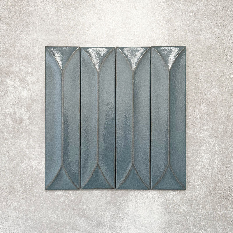 Baroque Decor Laguna Blue porcelain wall tile in a 9.1cm x 37.5cm format, featuring a deep blue metallic finish with a raised geometric relief design and gently distressed edges, displayed against a textured concrete-effect background.