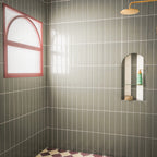 Contemporary walk-in shower featuring Baroque Lichen Green porcelain wall tiles in a vertical stacked layout, paired with a burgundy and white chequerboard floor, brushed brass shower fittings, an arched recessed niche and a statement red-framed window for a bold, modern bathroom design.