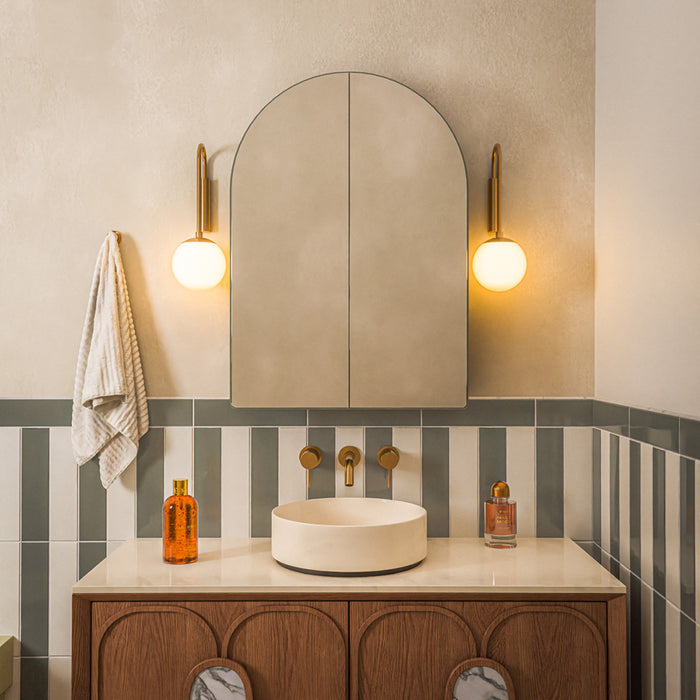 Contemporary bathroom featuring Baroque Lichen Green porcelain wall tiles in a vertical stacked layout, paired with a burgundy and white chequerboard floor, red framed shower screen, brushed brass fittings and a walnut vanity for a bold, design-led interior.