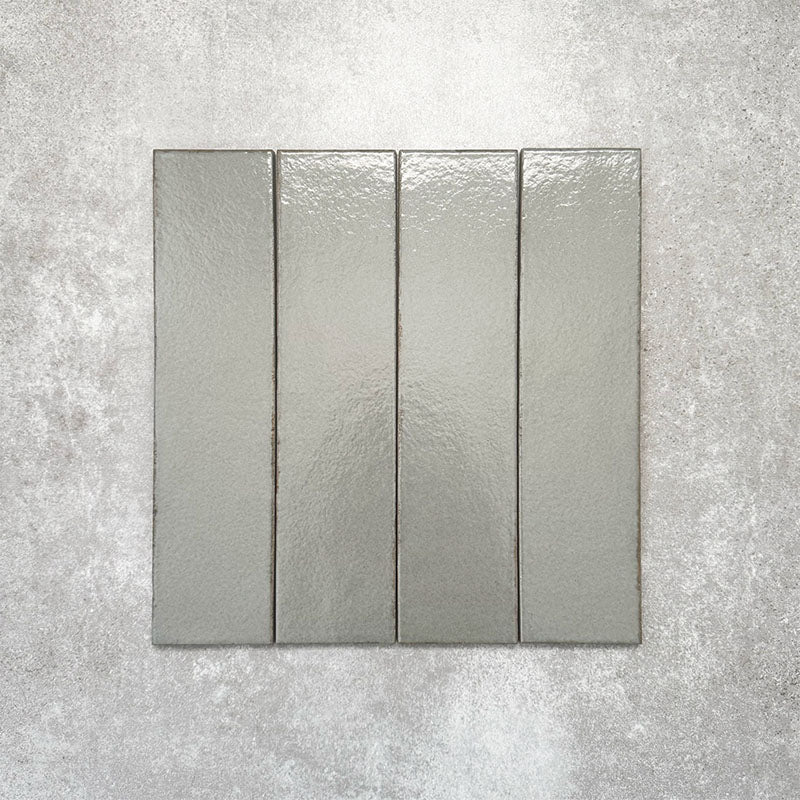 Baroque Lichen Green porcelain wall and floor tile in a 9.1cm x 37.5cm format, featuring a soft sage green metallic finish with gently distressed edges, displayed against a textured concrete-effect background.