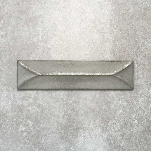 Baroque Decor Lichen Green porcelain wall tile in a 9.1cm x 37.5cm format, featuring a soft sage green metallic finish with a raised geometric relief design and gently distressed edges, displayed against a textured concrete-effect background.