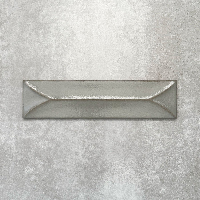 Baroque Decor Lichen Green porcelain wall tile in a 9.1cm x 37.5cm format, featuring a soft sage green metallic finish with a raised geometric relief design and gently distressed edges, displayed against a textured concrete-effect background.