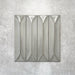 Baroque Decor Lichen Green porcelain wall tile in a 9.1cm x 37.5cm format, featuring a soft sage green metallic finish with a raised geometric relief design and gently distressed edges, displayed against a textured concrete-effect background.