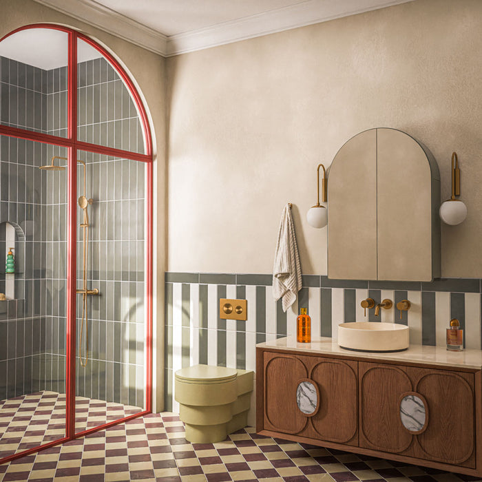 Contemporary bathroom featuring Baroque Vanilla porcelain wall tiles in a vertical stacked layout, paired with a burgundy and white chequerboard floor, walnut vanity, brushed brass fittings, an olive green WC and a striking red-framed shower enclosure for a bold, retro-inspired interior.