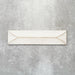 Baroque Decor Vanilla porcelain wall tile in a 9.1cm x 37.5cm format, featuring a soft cream metallic finish with a raised geometric relief design and gently distressed edges, displayed against a textured concrete-effect background.