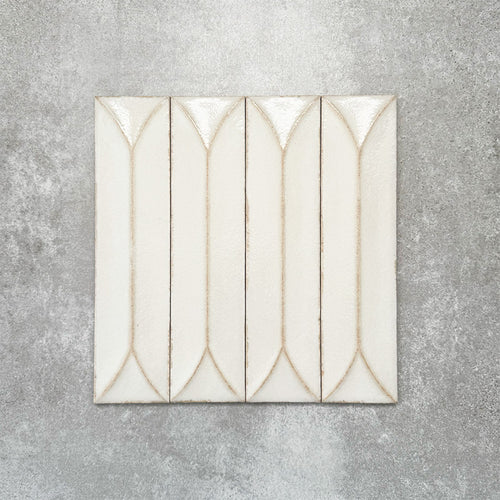 Baroque Decor Vanilla porcelain wall tile in a 9.1cm x 37.5cm format, featuring a soft cream metallic finish with a raised geometric relief design and gently distressed edges, displayed against a textured concrete-effect background.