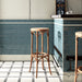 Bar interior featuring Pimlico River Blue 7.5 × 15cm ceramic wall tiles with a crackle glaze finish, laid in a classic brick pattern and paired with bar stools and patterned floor tiles.