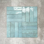 Nomad Aquamarine brick wall tiles in a 6 × 24.6cm format, shown laid in a basketweave layout with a glossy, lightly textured surface and soft blue-green tones, creating an industrial-style look.