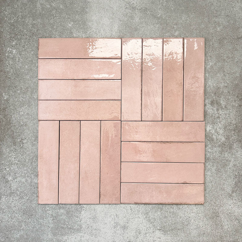 Nomad Rose brick wall tiles in a 6 × 24.6cm format, shown laid together in a basketweave layout to highlight the soft pink tone, gloss finish and subtle surface variation.