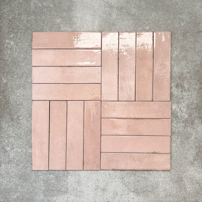 Nomad Rose brick wall tiles in a 6 × 24.6cm format, shown laid together in a basketweave layout to highlight the soft pink tone, gloss finish and subtle surface variation.