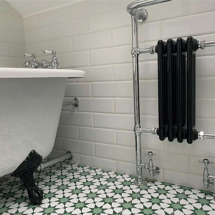 Bathroom setting featuring Agadir Green Moroccan-style 20x20cm porcelain floor tiles, showcasing a geometric star pattern in green and white, styled with a freestanding bath, white wall tiles and chrome fittings.