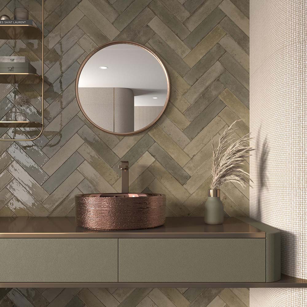 Bathroom wall featuring Allegra Sage Green Gloss Brick ceramic tiles in a 6 × 25cm format, laid in a herringbone pattern to create a calming, contemporary look with muted green tones and a glossy, handmade-style finish.